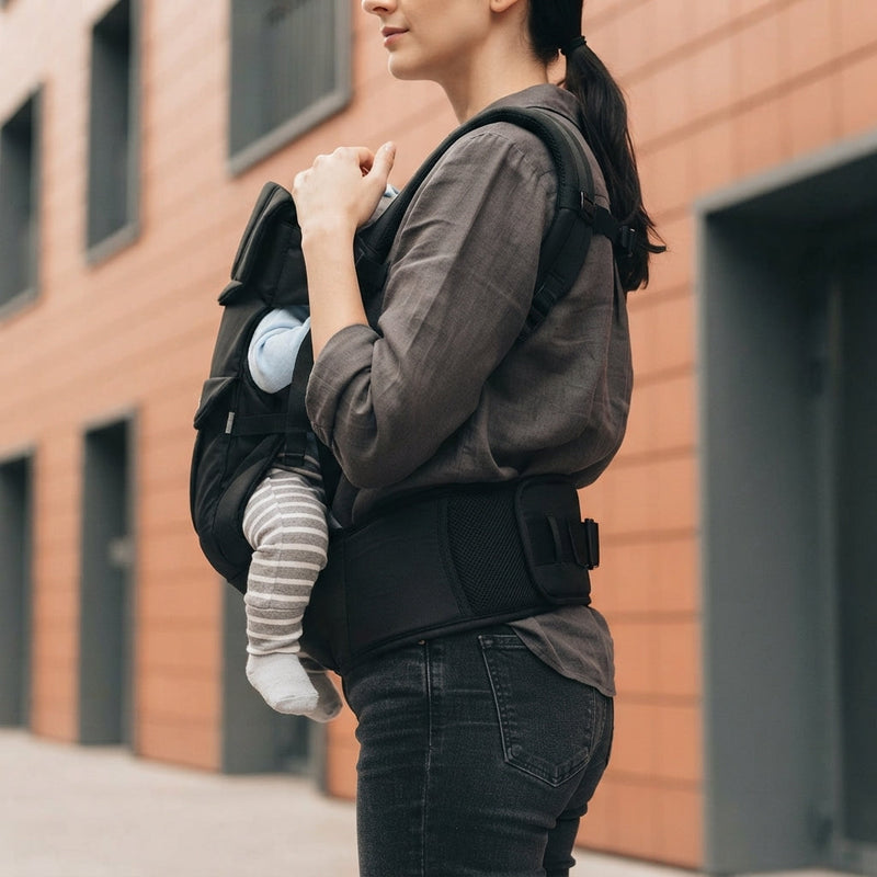 Detail of the ergonomic weight-distribution belt on a baby carrier worn by a woman to show lumbar support.